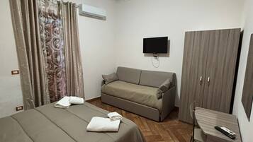 A hotel room with a bed, a sofa, a desk, a TV, and a wardrobe.