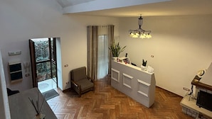 A spacious living area with a herringbone wooden floor, a built-in white entertainment unit, a large window with a view, and a herringbone staircase. - Home To Fly (Naples)