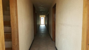 En smal hall med trädörrar på båda sidor och ett klinkergolv.