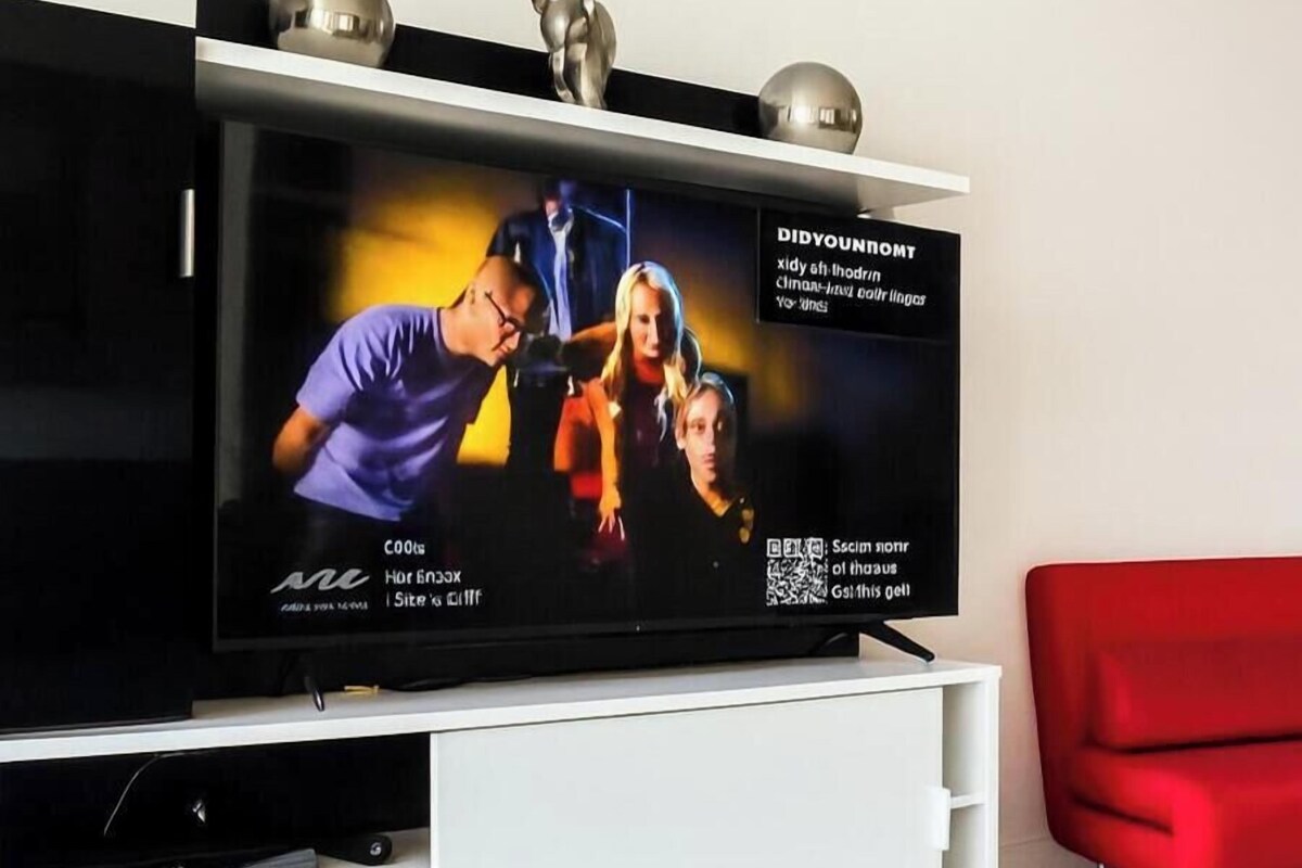A flat-screen TV on a white entertainment unit with a red chair nearby.