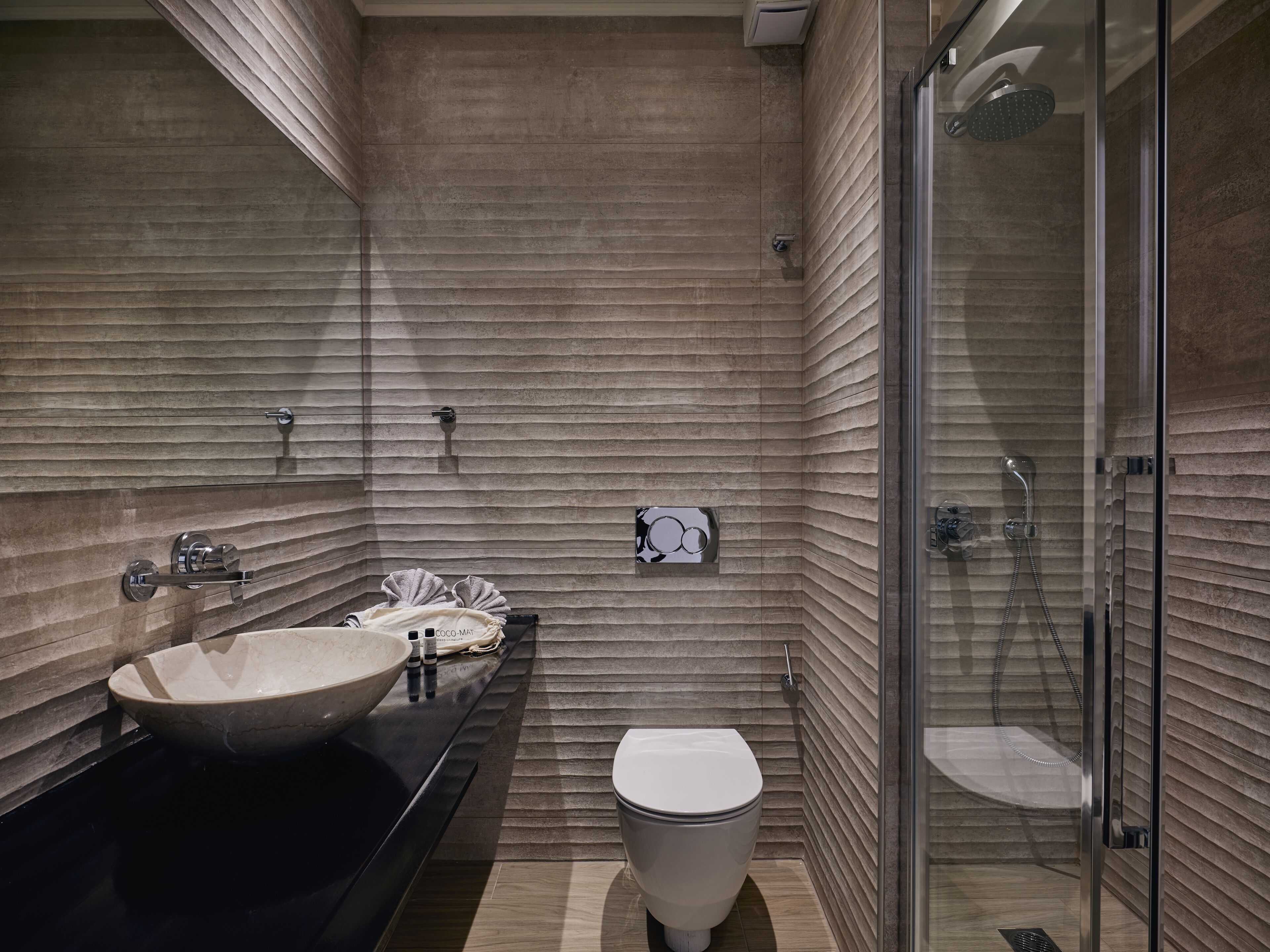 A modern bathroom with a large sink, toilet, and glass-enclosed shower.