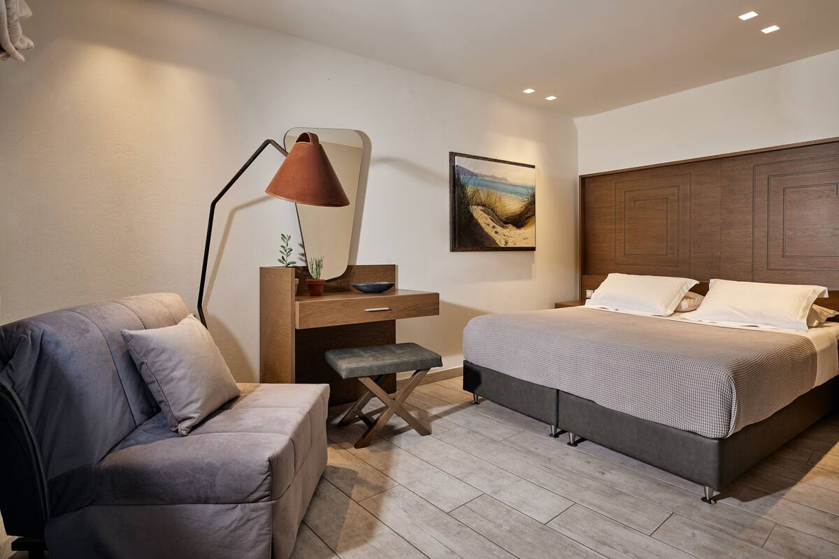 Un dormitorio con cama, escritorio, silla y mesita de noche.