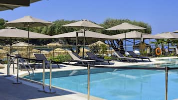Relax by the serene pool surrounded by lounge chairs and umbrellas, with a lifebuoy on hand for added safety.
