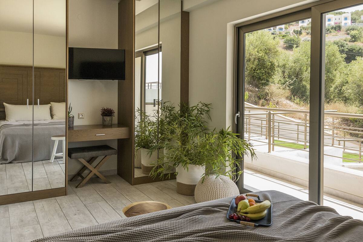 Un dormitorio moderno con una cama grande, un escritorio y un ventanal corredera que da a un balcón.