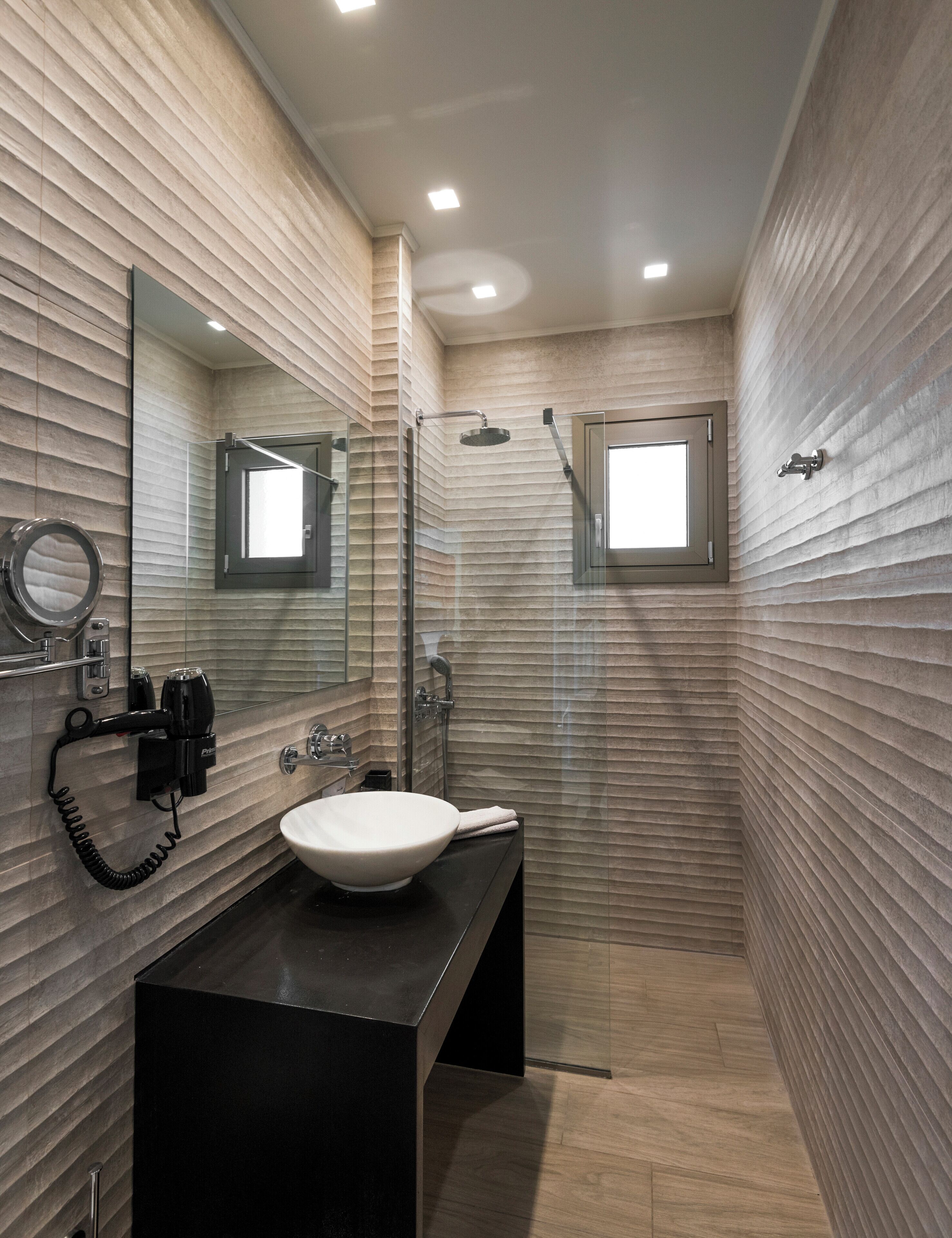 A modern bathroom with a large mirror, a sink, and a shower.