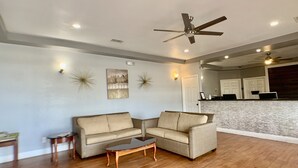 A living room with a beige sectional sofa, a glass coffee table, and a ceiling fan.