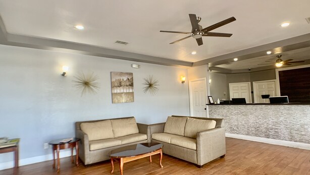 A living room with a beige sectional sofa, a glass coffee table, and a ceiling fan.