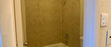 A bathroom with a bathtub, toilet, and a shower area.