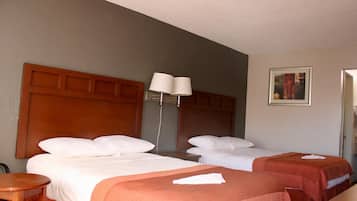 Una habitación de hotel con dos camas, una mesita de noche, una lámpara y un cuadro en la pared.
