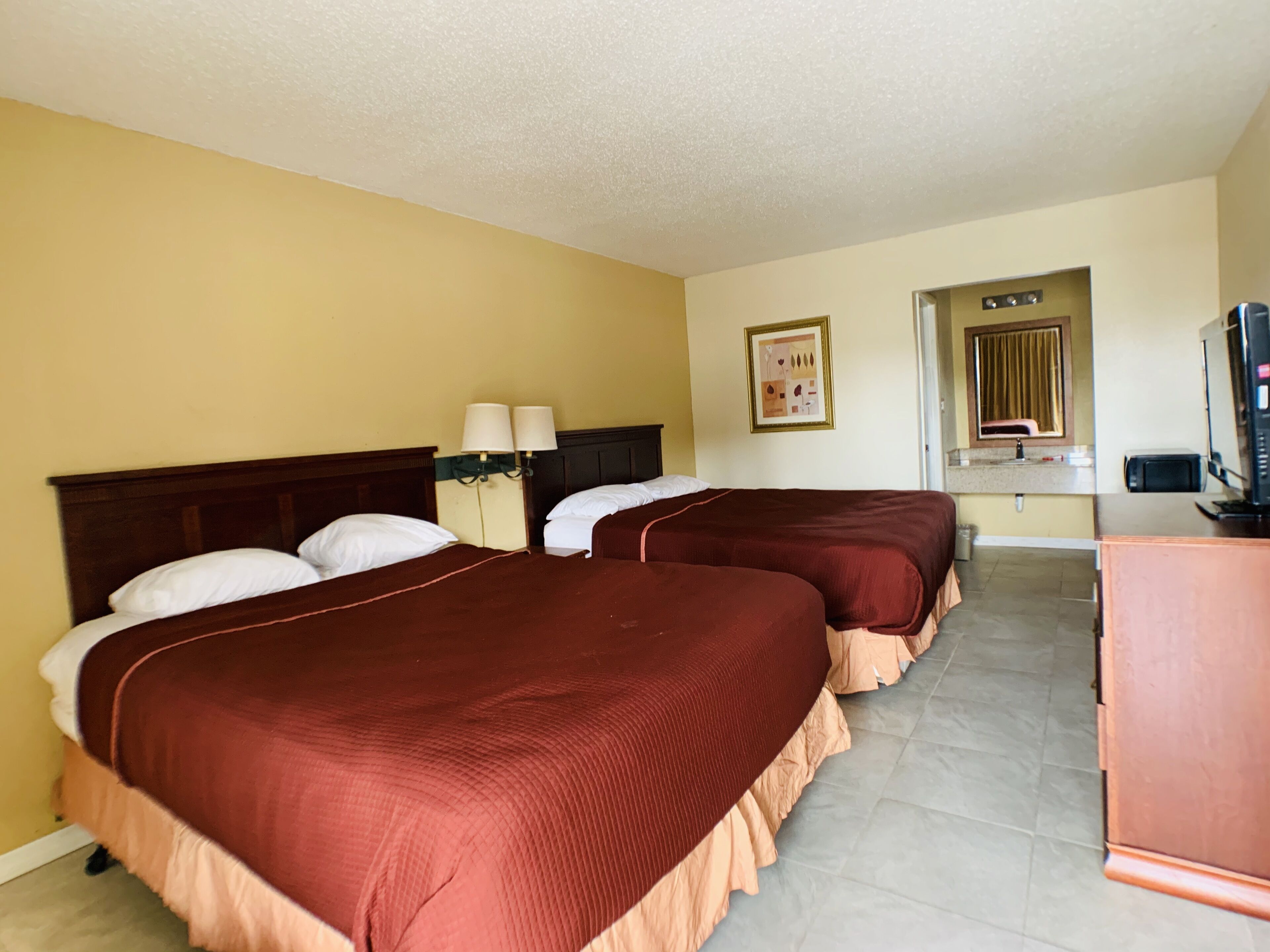 Habitación de hotel con dos camas, televisión, microondas y una pequeña kitchenette.