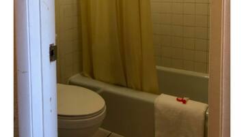 Un baño con inodoro, bañera y cortina de ducha.
