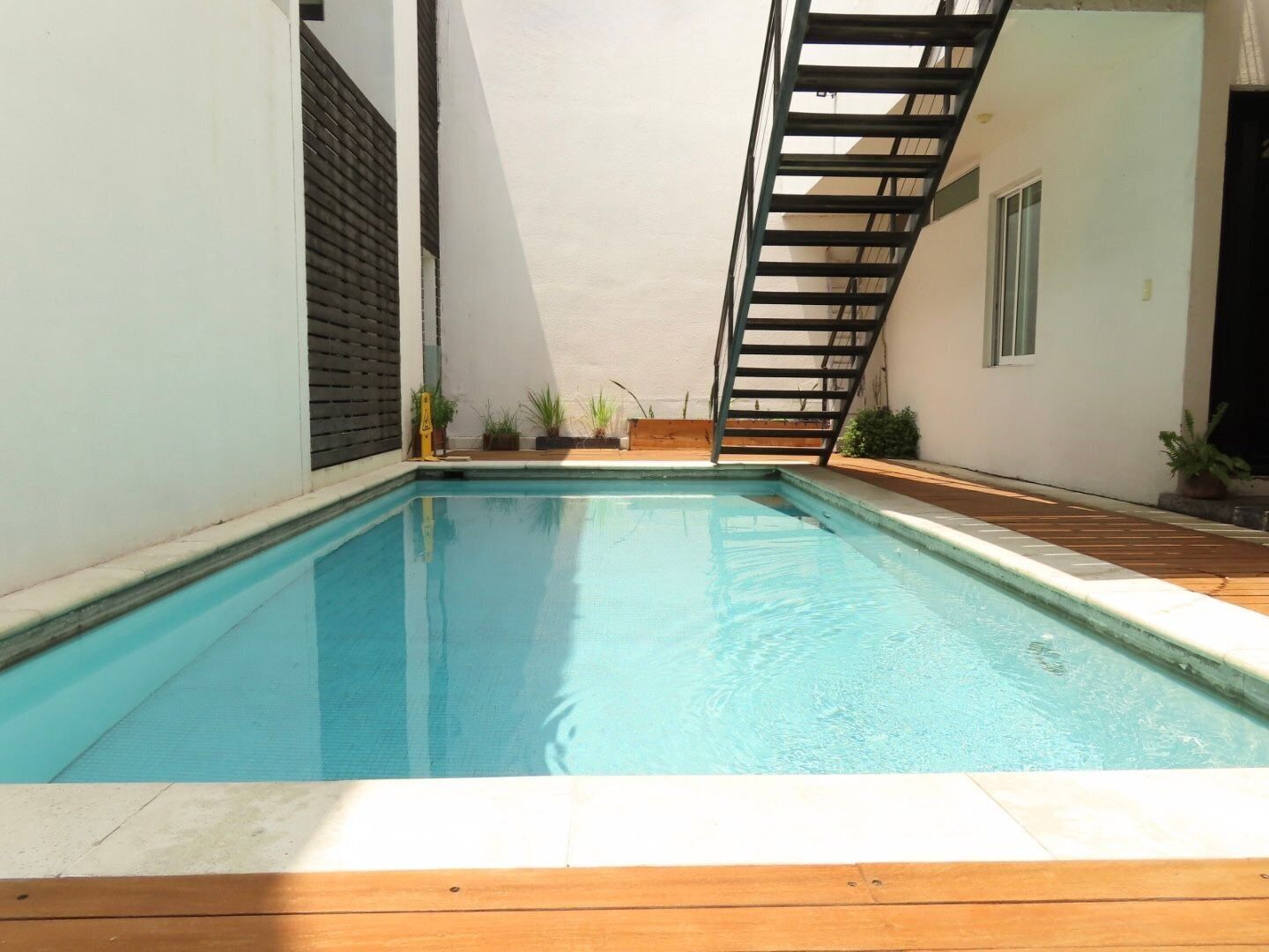 A rectangular swimming pool with a wooden deck in the foreground.