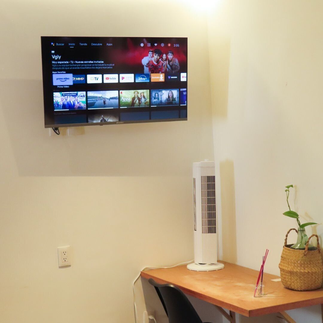 Un televisor de pantalla plana montado en la pared muestra una interfaz de servicio de streaming con múltiples opciones de contenido.