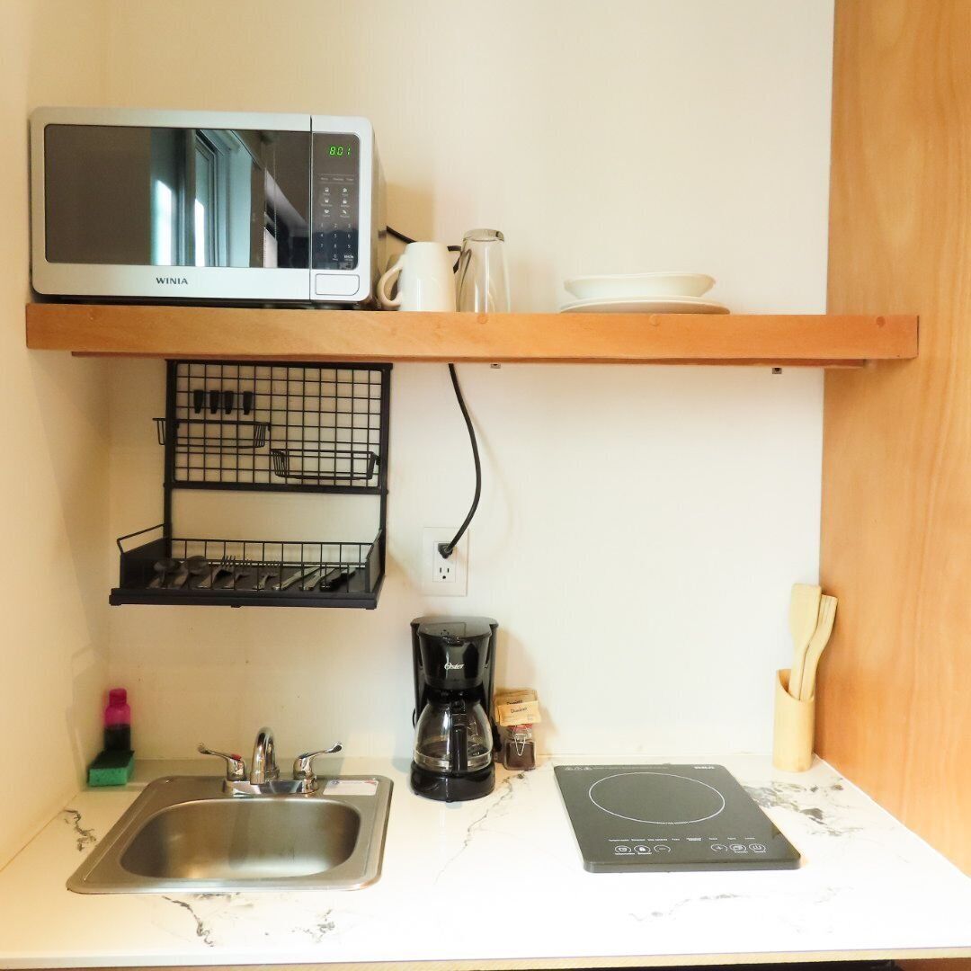 Una cocina compacta equipada con microondas, cafetera y placa de inducción.