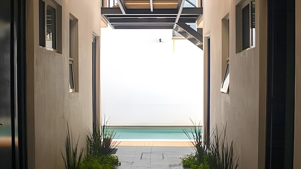 A pathway leading to a pool with a view of the sea, flanked by buildings with windows and plants. - 2NDHOME Celaya (Celaya)