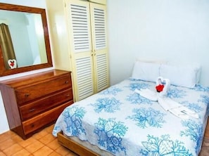 A bedroom with a bed, a dresser, a mirror, and a wardrobe. - Chai's Beach House (San Pedro)