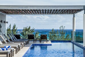 Una piscina infinitària amb gandules i vista a l'oceà.