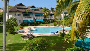 A resort with a swimming pool surrounded by lounge chairs, palm trees, and a well-maintained lawn. - Bay Pointe Yacht Club 2BD Apartment OLR (Montego Bay)