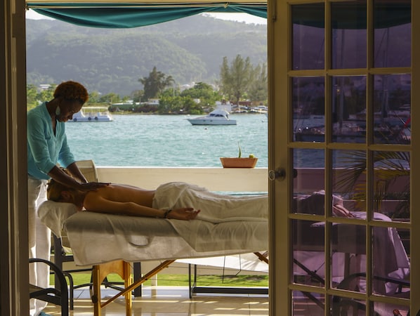 A massage therapy room with a view of the sea and boats.