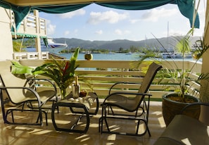 A balcony with outdoor furniture, a view of the sea, and a cruise ship in the background.