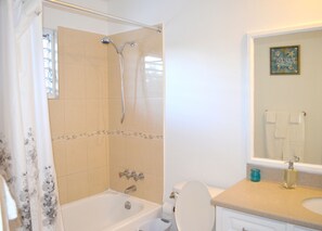 A bathroom with a bathtub, shower, toilet, and a sink with a mirror above it. - Bay Pointe Yacht Club 2BD Apartment OLR (Montego Bay)
