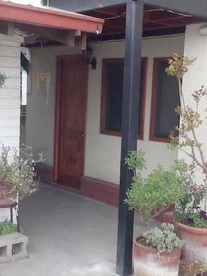 Un edificio con puerta de madera, una ventana y plantas en macetas.
