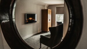 Et værelse med et fjernsyn ophængt på væggen, en træskab og en stol.