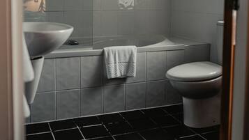 Une salle de bain avec un sol carrelé de noir, un lavabo blanc et des toilettes.