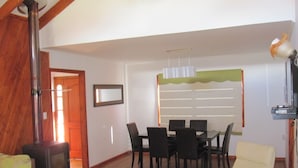 Un área de comedor con una mesa, sillas, una chimenea y un televisor.