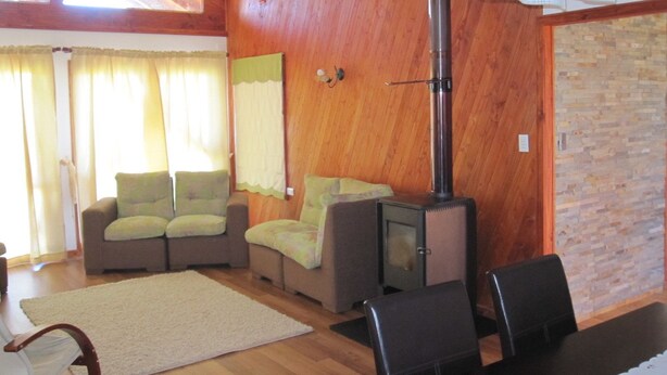 Un salón acogedor con paredes de madera, una chimenea y un comedor con mesa y sillas.