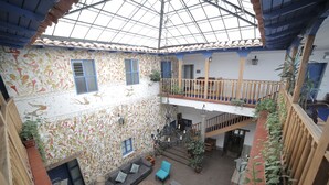 A spacious indoor courtyard with a high ceiling, a balcony, and a variety of seating areas. - Hotel Villa Mayor (Cusco)