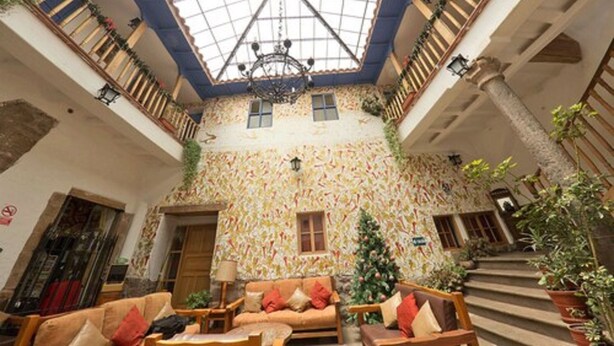 A spacious atrium with a high ceiling, a staircase, and a Christmas tree. - Hotel Villa Mayor (Cusco)
