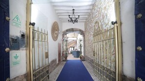 A corridor with a blue carpet, metal gates, and a chandelier. - Hotel Villa Mayor (Cusco)