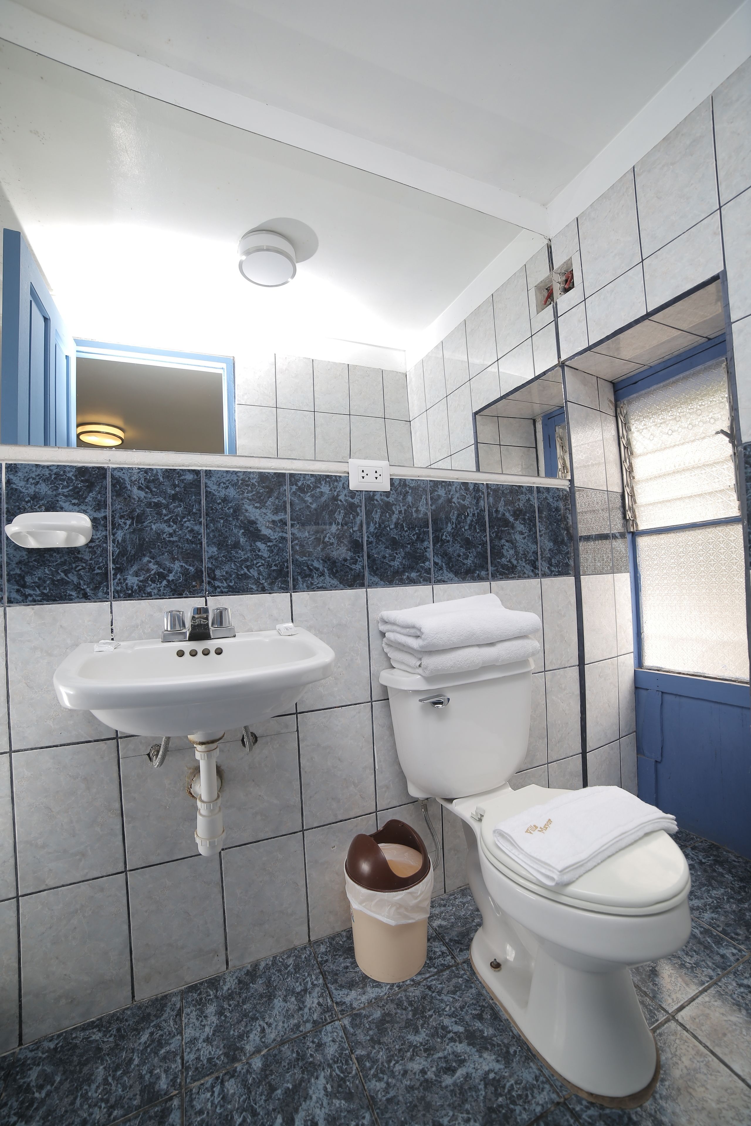 Een badkamer met een wit wastafel, toilet en blauwe betegelde wanden.