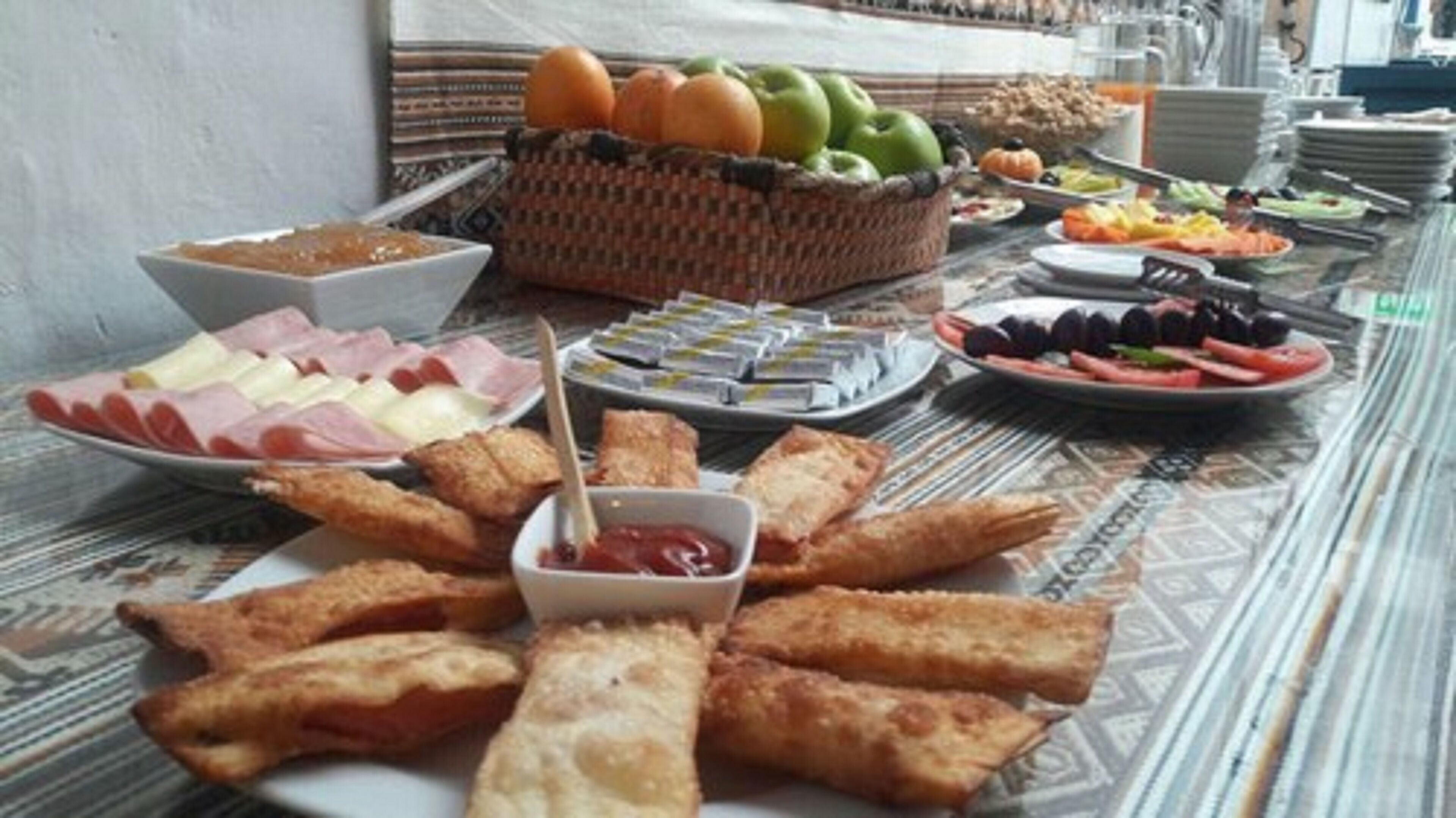 En buffetbord med forskellige retter, herunder friturestegte varer, frugt og en skål ketchup.