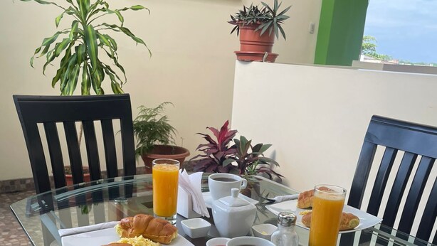 Una mesa de desayuno con platos de comida, una taza de café y vasos de jugo de naranja.