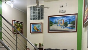 Una sala de estar con una escalera, un sofá de cuero negro, una mesa de centro y cuadros en las paredes.