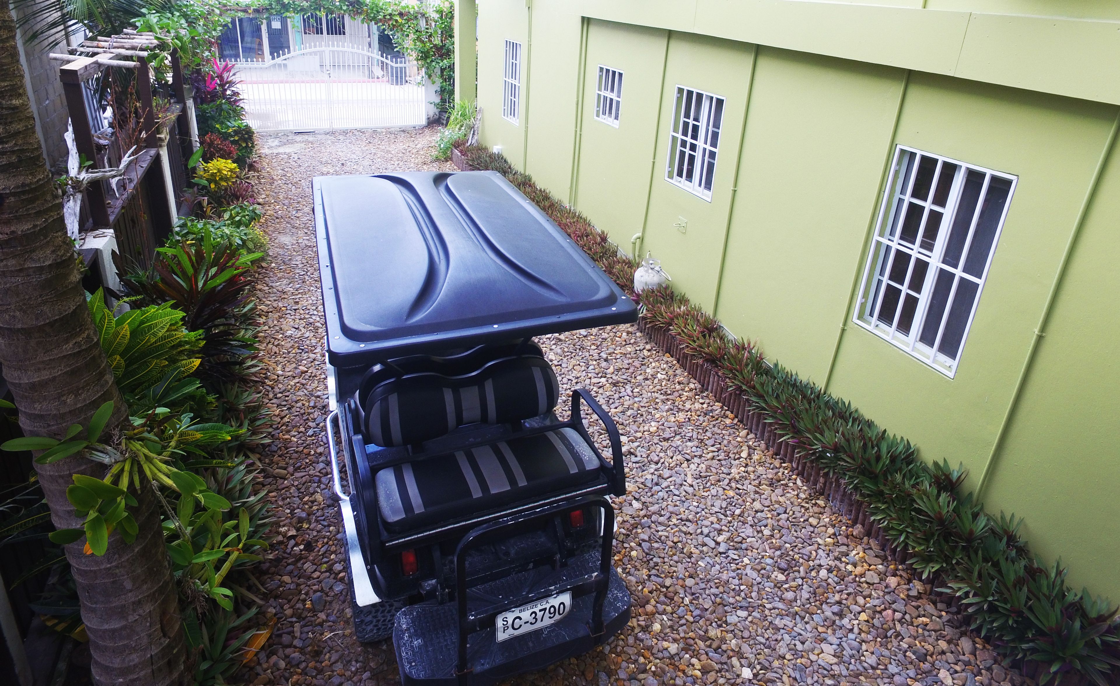 Un veicolo parcheggiato in un vialetto stretto, con un edificio verde su un lato.