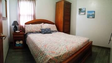 A bedroom with a bed, a nightstand, a lamp, a wardrobe, and two wall art pieces.