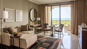 Habitación de hotel con cama, escritorio, silla, mesa de comedor y vista al océano.