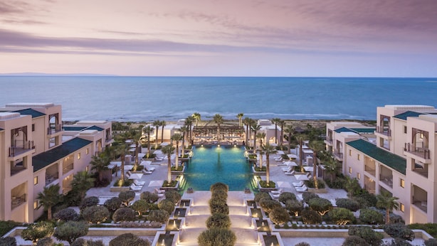 Un resort con piscina central, varios balcones y vista al mar.