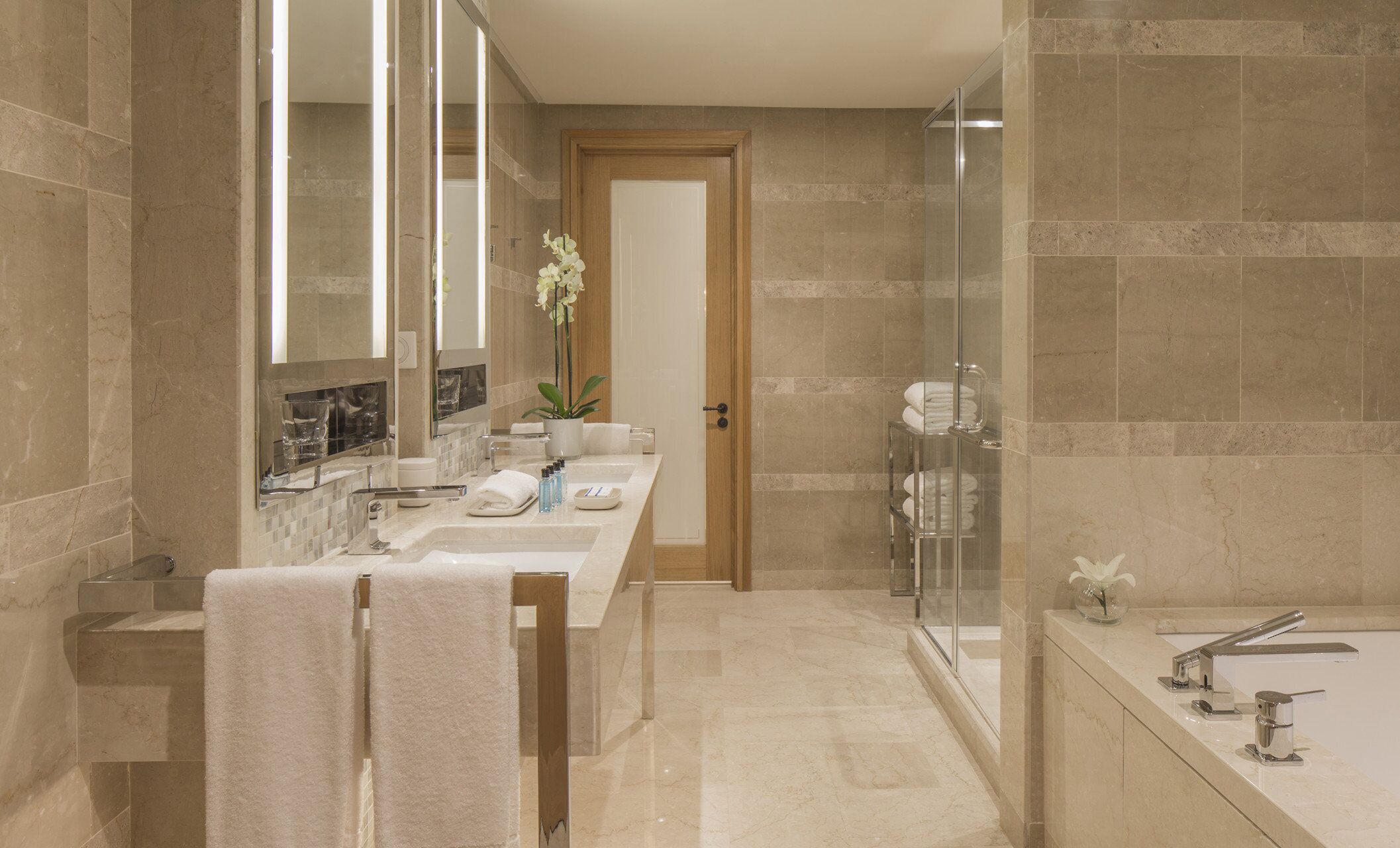 Un baño moderno con un espejo grande, cabina de ducha de vidrio y bañera.