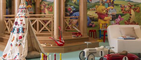 A playroom with a tent, toys, and a mural.