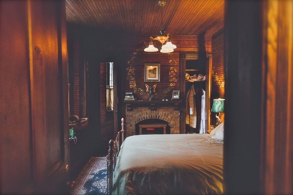 Una habitación acogedora con cama, chimenea y techo de madera.