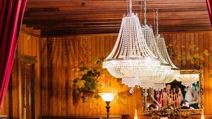 Un comedor formal con paneles de madera, sillas tapizadas en rojo y un candelabro.