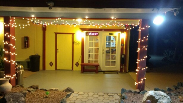 A building with a yellow exterior, a door labeled "MANCY," and a bench outside. - Marine Motel (Ajo)