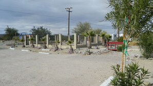 A parking lot with a gated entrance, palm trees, and a red bench. - Marine Motel (Ajo)