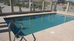 A swimming pool with a metal ladder and a fence. - Marine Motel (Ajo)