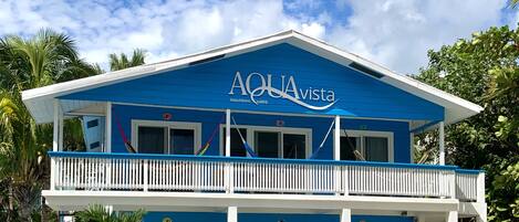 En toetages bygning med en blå facade og et skilt der siger "AQUAvista beachfront suites".