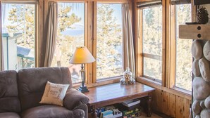 A cozy cabin interior with wooden walls and ceiling, a cushioned sofa, a small table with a lamp, and a stone fireplace. - Lake Views! Perfect Mountain Summer Get-a-way No traffic, 8,000 ft. elevation (Stateline)